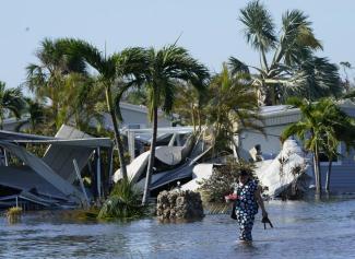 Holly Nugyn walks out of her flooded neighborhood after Hurricane Ian passed by the area Thursday, Sept. 29, 2022, in Fort Myers, Fla. (AP Photo/Steve Helber)