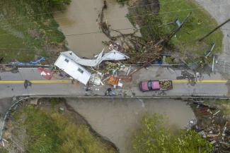 People work to clear a house from a bridge near the Whitesburg Recycling Center in Letcher County, Ky., on Friday, July 29, 2022. (Credit: Ryan C. Hermens/Lexington Herald-Leader via AP)