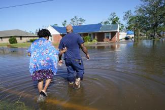 FILE - Soncia King holds onto her husband, Patrick King, in Lake Charles, La., Saturday, Oct. 10, 2020, as they walk through the flooded street to their home, after Hurricane Delta moved through the previous day. According to a study published in Nature Communications on Tuesday, April 12, 2022, climate change made the record-smashing deadly 2020 Atlantic hurricane season noticeably wetter. (Credit: AP Photo/Gerald Herbert, File)