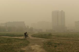 A man rides his bicycle through smoke from a forest fire covers Yakutsk, the capital of the republic of Sakha also known as Yakutia, Russia Far East, Russia, Thursday, Aug. 12, 2021. The U.N. weather agency has certified a 38-degree Celsius (100.4 Fahrenheit) reading in the Russian town of Verkhoyansk last year as the highest temperature ever recorded in the Arctic. The World Meteorological Organization said the temperature "more befitting the Mediterranean than the Arctic" was recorded in June 2020 during 
