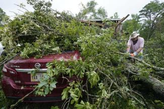 FILE - Span McGinty uses his chain saw to cut fallen tree limbs from a tornado-damaged vehicle at his brother's house in Yazoo County, Miss., on May 3, 2021. 90% of counties in the United States experienced a weather-related disaster between 2011-2021, according to a report published on Wednesday, Nov. 16, 2022. Over 300 million people — 93% of the country’s population — live in those counties. (Credit: AP Photo/Rogelio V. Solis, File)