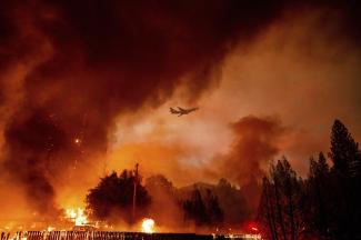 An air tanker flies above the Oak Fire burning in Mariposa County, Calif., on Friday, July 22, 2022. (Credit: AP Photo/Noah Berger)