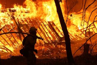 A California Department of Forestry and Fire Protection firefighter is pictured monitoring a burning home as the Camp Fire moved through the area Nov. 9, 2018, in Magalia, Calif. (Credit: Justin Sullivan/Getty Images)