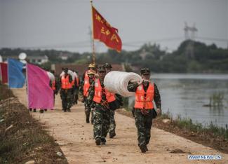 Armed police soldiers prepare for the breach of the embankment on the dike of Niushan Lake in central China's Hubei Province, July 13, 2016. The Hubei provincial government Tuesday decided to break the embankment between Liangzi Lake and Niushan Lake, to prevent possible flood overflow over the dike. The operation will be executed on July 14. Photo: Xiao Yijiu, Xinhua