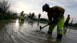 A Cal Fire crew member is shown standing in water, working to build a trench. 