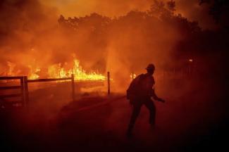 FILE - A firefighter runs to extinguish flames as the Oak Fire crosses Darrah Road in Mariposa County, Calif., on July 22, 2022. Crews were able to to stop it from reaching an adjacent home. Costly weather disasters kept raining down on America last year, pounding the nation with 18 climate extremes that caused at least $1 billion in damage each, totaling more than $165 billion, federal climate scientists calculated Tuesday, Jan. 10, 2023. (AP Photo/Noah Berger, File)
