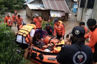 Members of the Philippine Coast Guard assist residents affected by floods during a rescue operation, in Lamitan City, Basilan province, January 11, 2023 (Credit: Philippine Coast Guard/Handout via Reuters)