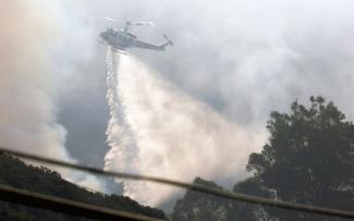A Cal Fire water-dropping helicopter is pictured as the so-called Colorado Fire burns near Big Sur, Calif., on Jan. 22, 2022. (Credit: Peter DaSilva / Reuters)