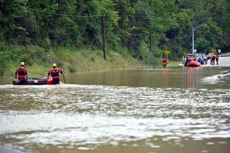 Members of the Winchester, Kentucky, Fire Department walk inflatable boats across flood waters over Kentucky State Road 15 in Jackson, Kentucky, to pick up people stranded on Thursday, July 28. (Credit: Timothy D. Easley/AP)
