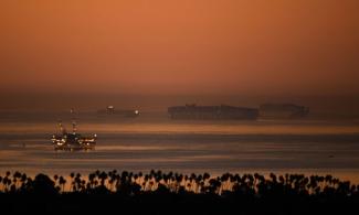 An oil platform stands offshore as cargo shipping container ships wait in the Pacific Ocean to enter the port of Los Angeles. (Photograph: Patrick T Fallon/AFP/Getty Images)