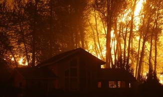 A wildfire burns behind a home in Twisp, Washington, in August 2015. Photo: Ted S. Warren, AP