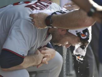 Minnesota Twins' Brian Dozier has a cold wet towel applied to his head during the seventh inning of a baseball game Chicago Cubs Saturday, June 30, 2018, in Chicago. Temperatures at Wrigley Field climbed into the mid 90's with a heat index over 100 degrees. Credit: Charles Rex Arbogast, AP