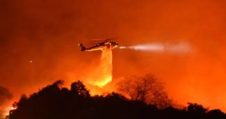 A Los Angeles County Firehawk copter makes a water drop on flames off CA Highway 154 north of Foothill Road. Credit: Mike Eliason / Santa Barbara County Fire