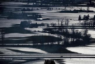 A police vehicle, bottom right, travels on the Trans-Canada Highway past flooded farmland in Abbotsford, British Columbia, on Wednesday, Nov. 17, 2021. (Darryl Dyck/The Canadian Press via AP)