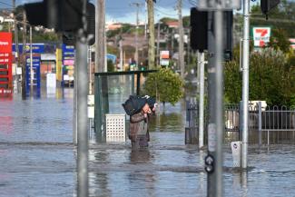 A man wades through floodwaters amidst evacuation orders in the Maribyrnong suburb of Melbourne, Australia, October 14, 2022. Credit: AAP Image/Erik Anderson