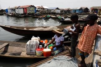 A woman sits in a canoe as she sells food to children at the Makoko fishing community on the Lagos Lagoon, Nigeria February 26, 2022. (Credit: REUTERS/Temilade Adelaja)