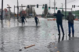 Caylon Coomes left, and another man prepare to paddleboard in floodwaters on city streets in Bellingham, Wash., Monday. (Lisa Baumann/AP)