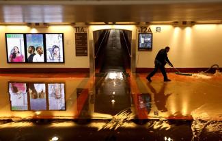 Metro worker Gerardo Medina, 21, clears a flooded section of the pedestrian walkway leading to train platforms on the main level of Union Station in downtown Los Angeles on Tuesday.(Genaro Molina / Los Angeles Times)