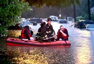Steven Bertke and his dog Roscoe are taken to dry land by St. Louis firefighters who used a boat to rescue people from their flooded homes on Hermitage Avenue in St. Louis on Tuesday, July 26, 2022. Credit: David Carson/AP