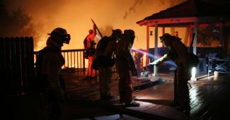 Firefighters work to save a home from an encroaching fire during the Lilac fire in Bonsall, California on Thursday, December 7, 2017. Credit: Sandy Huffaker, AFP, Getty Images