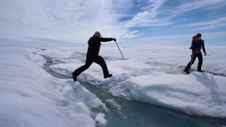 A scientist leaps over water during a trip to the Greenland ice sheet, which saw melting over more than 50% of its surface last year. Photo: Joe Raedle/Getty Images