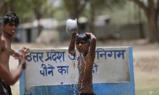 Indian boys bath at a drinking water tap on a hot day in Prayagraj, India. Photo: Rajesh Kumar Singh, AP
