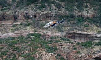 A helicopter flies above the rugged terrain along the banks of the East Verde River during a search and rescue operation for victims of a flash flood, July 16, 2017, in Payson, Ariz. Photo: ABC News