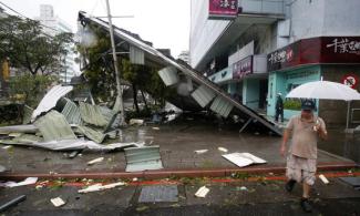 A man passes a damaged structure from Typhoon Soudelor in Taipei, Taiwan, on Aug. 8th. Photo: Wally Santana, AP