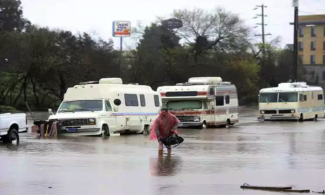 A man who lives in his RV in Salinas, Calif., walks through the flooded street on Mon., Feb. 20, 2016. Photo: Nic Coury, AP