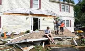 Brandon Testerman, 14, and his dog Tippy, sit on what was once part of his home's roof as other family remove belongings from the home in Bay City, Maryland, Monday, July 24, 2017. Photo: Paul W. Gillespie, The Baltimore Sun