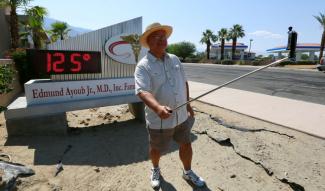 Palm Springs resident Benito Almojuela takes a selfie near a thermometer sign which reads 125 degrees in Palm Springs, California, June 20, 2016. Photo: Sam Mircovich / Reuters