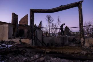 A man digs through debris at his parent's home in a neighborhood decimated by the Marshall Fire on Jan. 2 in Louisville, Colo. Officials reported that 991 homes were destroyed in the blaze, making it the most destructive wildfire in Colorado history. (Michael Ciaglo/Getty Images)