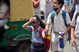 School students are seen outside a school on a hot summer day on April 26 in New Delhi. (Credit: Raj K Raj—Hindustan Times/Getty Images)
