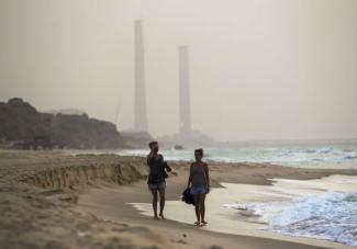 Tourists walk at the shore of the Mediterranean sea in Ashkelon in southern Israel during heavy hazy weather in the region. (photo credit:REUTERS)