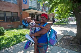 Michelle Braxton holds her daughter, Dior Braxton, 4, after an early dismissal of classes at Franklin Square Elementary/Middle School in Baltimore because of inadequate cooling in the building amid high temperatures on May 31, 2022. (Credit: Vincent Alban/The Baltimore Sun/AP)