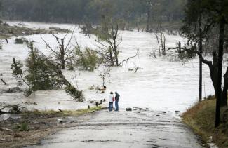 Jim Richardson and his wife Jeannette look on as the Blanco River recedes after the flash flood in Wimberly, Texas Friday, Oct. 30, 2015. A fast-moving storm packing heavy rain and destructive winds overwhelmed rivers and prompted evacuations Friday in the same area of Central Texas that saw devastating spring floods. Image credit: Ricardo Brazziell/Austin American-Statesman via AP.
